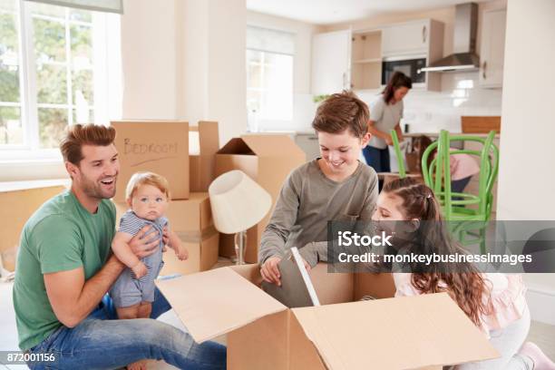 Children Helping Parents To Unpack On Moving In Day Stock Photo - Download Image Now