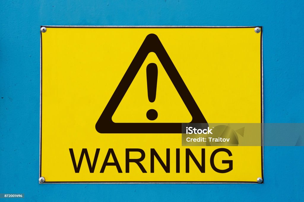 Warning sign on yellow metallic board Closeup view of street warning exclamation sign on yellow metallic board Danger Stock Photo