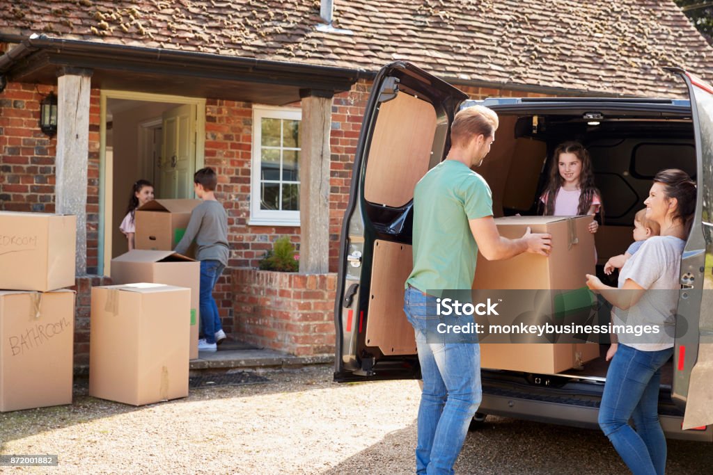 Family Unloading Boxes From Removal Truck On Moving Day Moving House Stock Photo