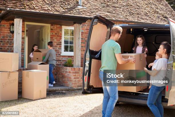 Family Unloading Boxes From Removal Truck On Moving Day Stock Photo - Download Image Now