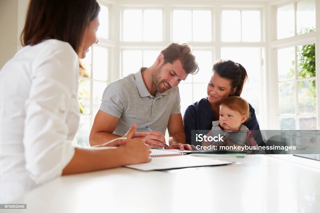 Family With Baby Meeting Financial Advisor At Home Family Stock Photo
