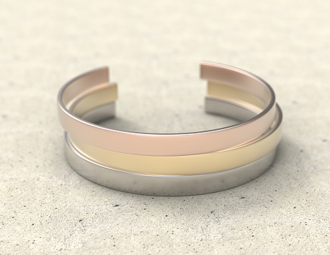 Solid metal bracelet in three colors on a stone table. Mockup close-up.