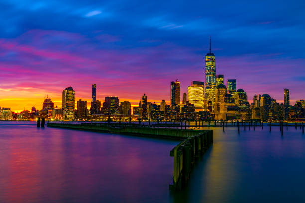 break of dawn the color of the sky and the lights of the Manhattan skyline reflect off the Hudson river looking from New Jersey.
