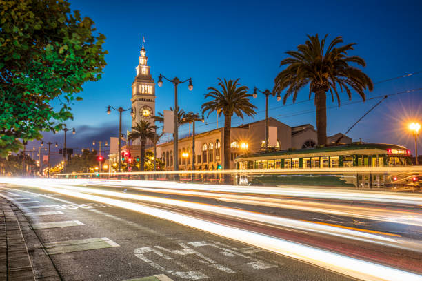 Traffic at night in front San Francisco Ferry Building Long exposure image of traffic at night in front San Francisco Ferry Building. blurred motion street car green stock pictures, royalty-free photos & images