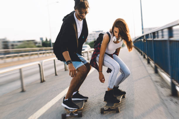 istock Young attractive couple riding skateboards and having fun 872009322