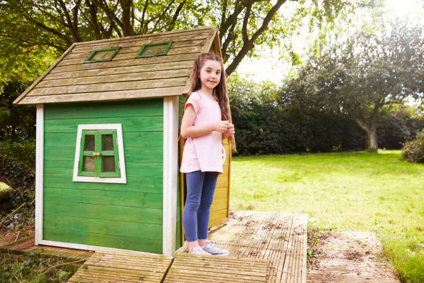 Portrait Of Girl Standing In Garden Next To Playhouse Portrait Of Girl Standing In Garden Next To Playhouse playhouse stock pictures, royalty-free photos & images