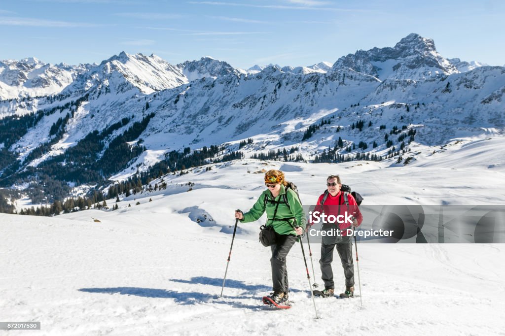 Couple de personnes âgées est la randonnée en raquettes dans la montagne alpine hivernale. Bavière, Allemagne. - Photo de Raquette à neige libre de droits