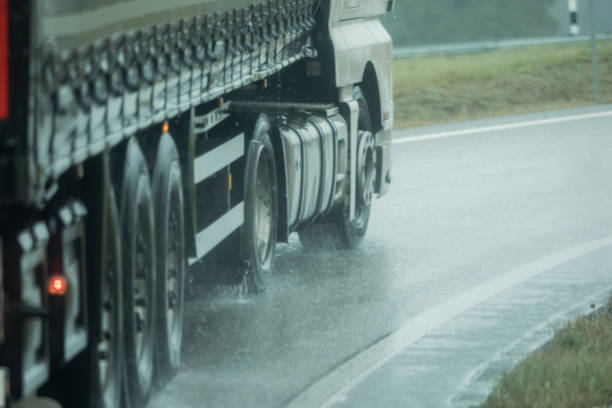 A truck is driving on the road in the rain stock photo