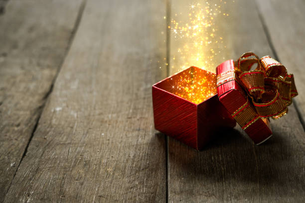 istock Red Christmas gift box with gold magic lights on wooden desk 872042052
