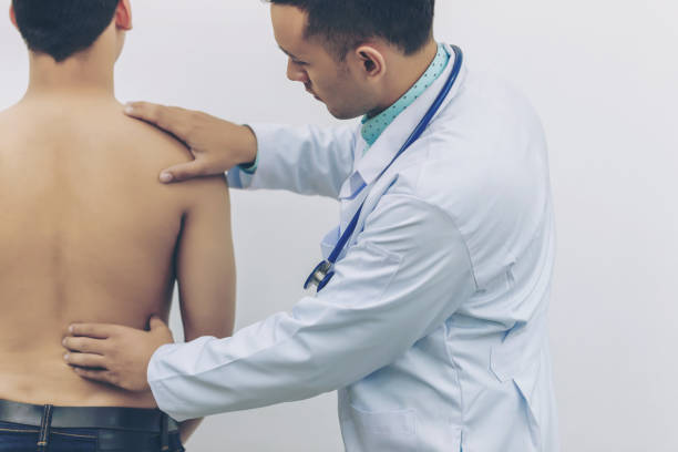 médico toca a placa traseira para causas de dor nas costas com estetoscópio no hospital. conceito de exame físico, médico e de saúde. - physical labor - fotografias e filmes do acervo