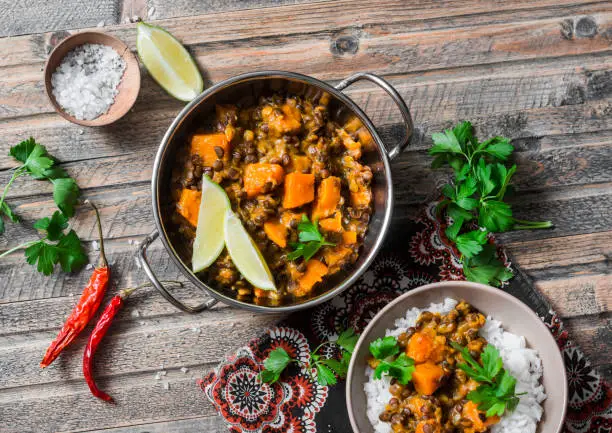 Pumpkin lentil curry and rice on a wooden table, top view. Indian vegetarian food concept