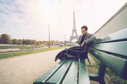 Young businessman reading a book in Paris, Eiffel Tower on the background. People travel business relaxation concept