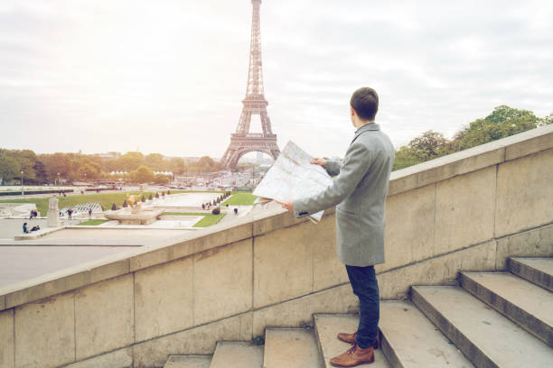 istock Businessman visiting Paris, holding street map - Eiffel Tower 872053100