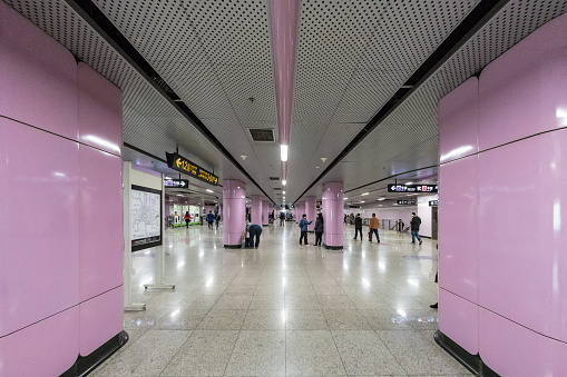 People walking the corridors of a pink subway station in Shanghai, China.