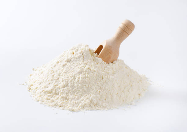 pile of wheat flour and wooden scoop on white background