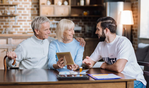 istock Two cheerful pensioners spending time with their young social worker 872062712