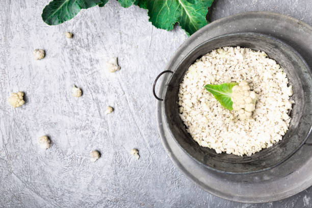 istock Cauliflower rice in metal bowl on grey background. Top view. Overhead. Copy space. Shredded 872067026
