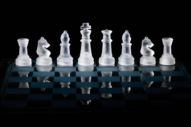 istock Glass Chess Set Standing on a Chessboard with a Dark Background, including the Rook, Knight, Bishop, Queen and King Pieces 872077314