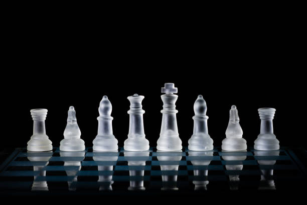 istock Glass Chess Set Standing on a Chessboard with a Dark Background, including the Rook, Knight, Bishop, Queen and King Pieces 872077382
