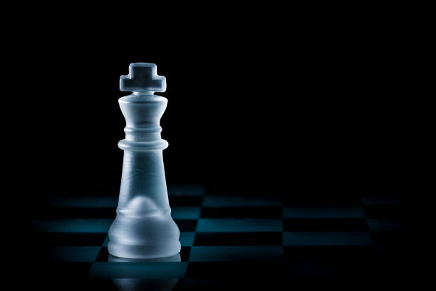 istock Glass King Chess Piece Stands Alone on Chessboard with Dark Background 872077432