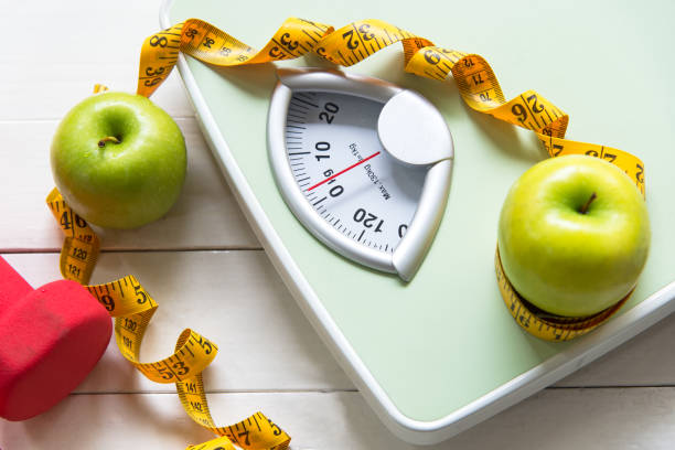 mela verde con scala di peso e metro per la dieta sana dimagrante. dieta e concetto sano - weights dieting apple healthy eating foto e immagini stock