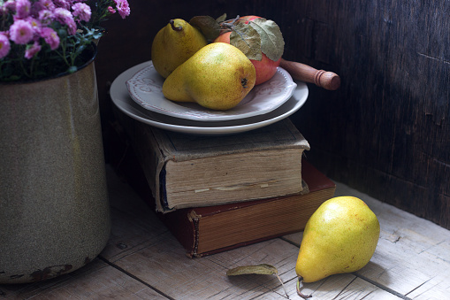 Autumn still life with pears, apple, chrysanthemums and books. Rustic style, selective focus.