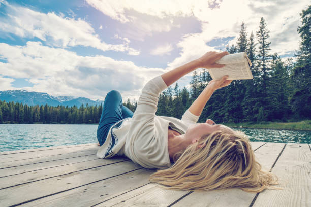 Pretty Woman happy smiling and read books on the field near the lake