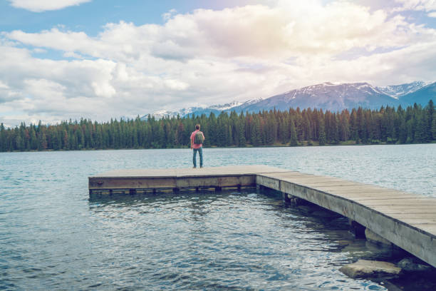 istock Young man standing by the lake looking at mountain scenery 872096280