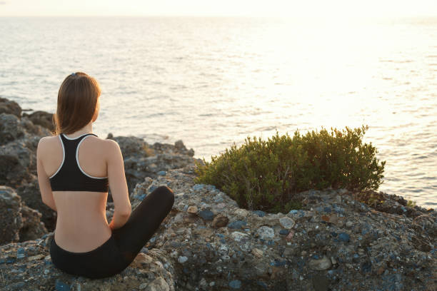 istock Girl meditating on the beach at sunset 872101486