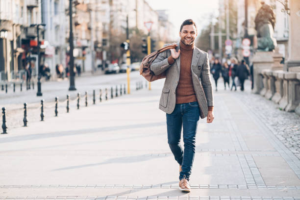 giovane con borsa che cammina per strada - blazer men suit business foto e immagini stock