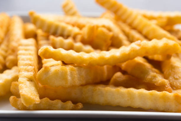 istock French fries in a white plate on a wooden table. 872112246