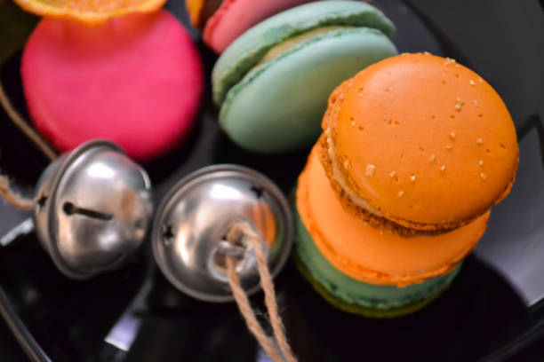 istock French macaroon pastry cookies (macarons, macaroni) on a black shiny plate with bells 872116332