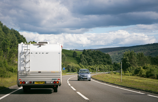 Inverness-shire, Scotland, UK - A car passing a Laika motorhome on a curving section of the A9 trunk road in Scotland's highlands.