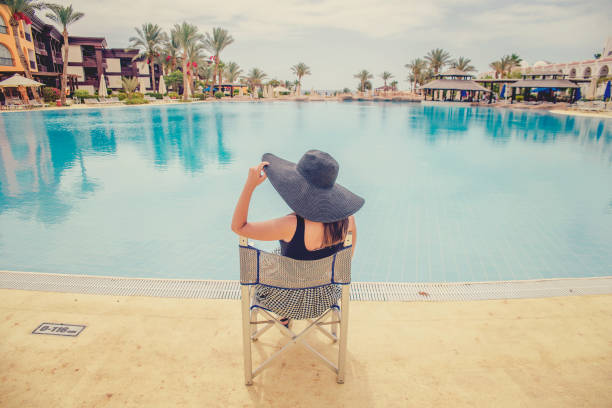 istock woman in black hat near the pool 872119420