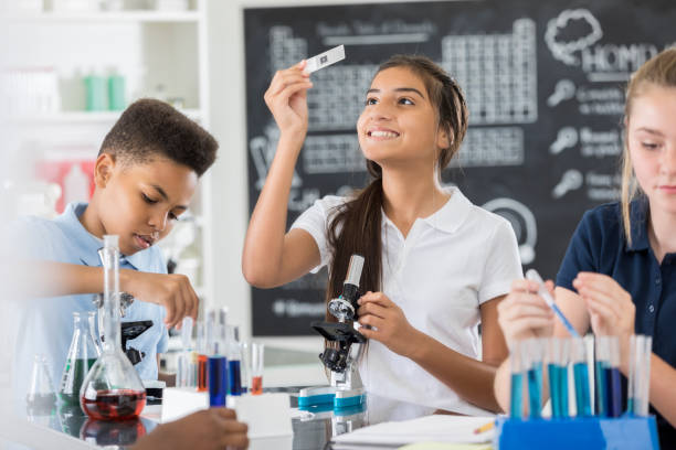 hispanische mittelschule schüler untersucht objektträger - science education child classroom stock-fotos und bilder