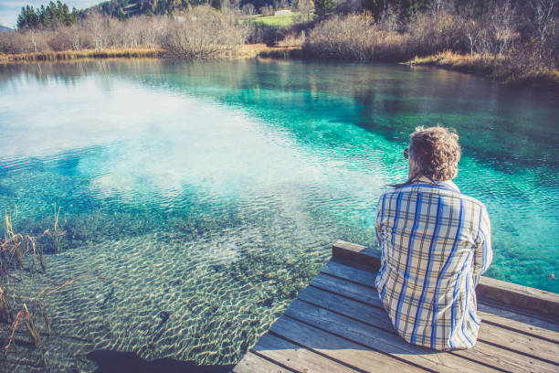 Senior Man by the green lake. Alps, Europe. All logos removed. Nikon.