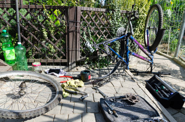 vélo cassé, remplacement de la roue et l’essieu. dans le fond des pièces et outils. - bicycle broken old chain photos et images de collection