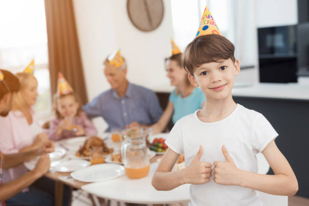 tummen upp. en pojke som poserar mot bakgrund av en familj som samlades vid en festlig bord - boy and girl in kitchen thumbs up bildbanksfoton och bilder