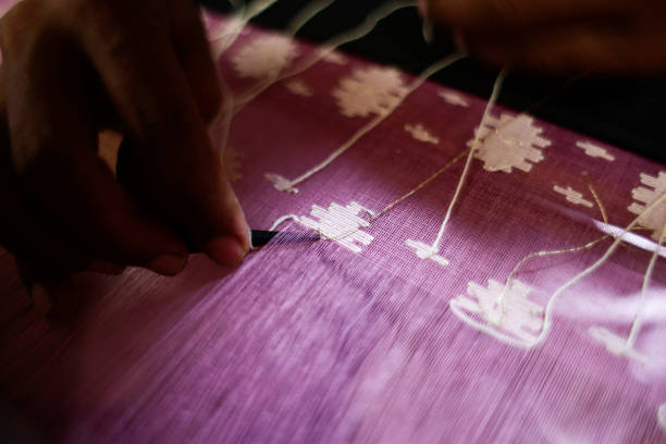 Handloom weaver weaves Jamdani saree on a traditional wooden hand weaving loom at Tarabo, near Dhaka, Bangladesh, August 24, 2016. Jamdani is one of the finest muslin textiles of Bengal, produced in Dhaka District, Bangladesh for centuries.  The historic production of jamdani was patronized by imperial warrants of the Mughal emperors. Under British colonialism, the Bengali Jamdani and muslin industries rapidly declined due to colonial import policies favoring industrially manufactured textiles. In more recent years, the production of Jamdani has witnessed a revival in Bangladesh. The traditional art of weaving Jamdani has been declared by UNESCO as an Intangible Cultural Heritage of Humanity.