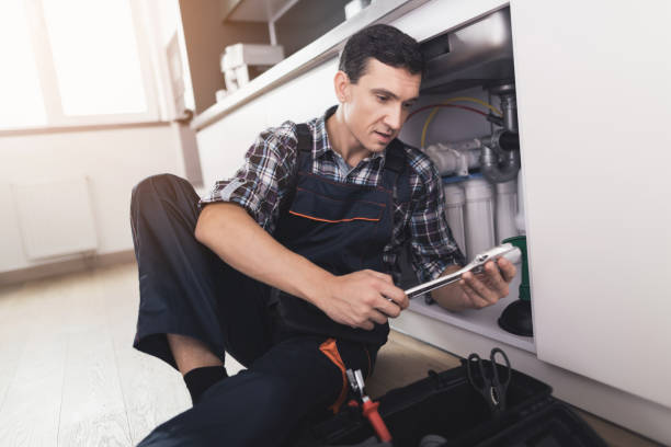 istock The plumber sits next to the kitchen sink on the floor and selects the appropriate spanner for repairing the pipe. 872170414