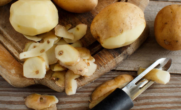 istock Raw potatoes with a vegetable peeler 872174668