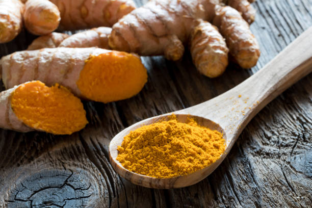 istock Ground turmeric on a wooden spoon, with fresh turmeric root 872177646