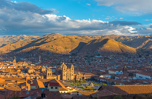 The cityscape of Cusco, the ancient Inca capital, with the Andes mountain range in the background at sunset, Peru.
