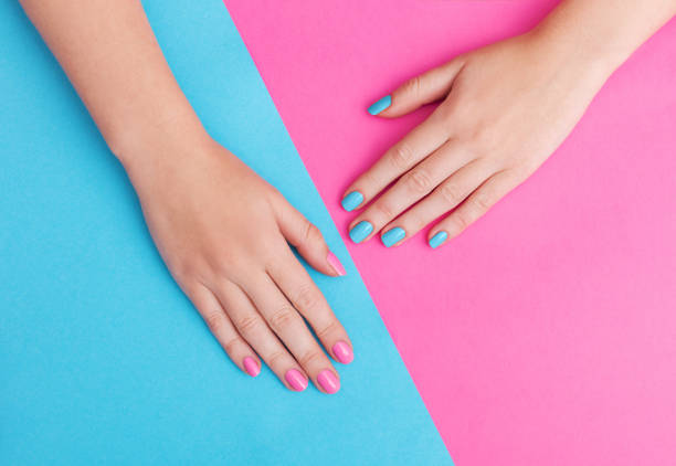 primo piano delle mani di una giovane donna con manicure sulle unghie su sfondo rosa - fingernail nail polish women human hand foto e immagini stock