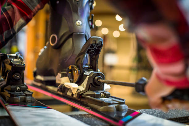 Sales Assistant adjusting ski boots and binding on skis. stock photo