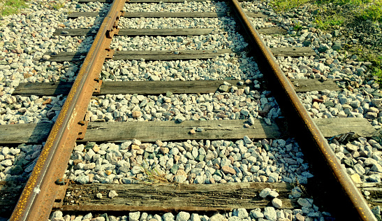 Tight shot of the metal rails and wood ties on gravel stones of an old railroad train track in Galveston, Texas.