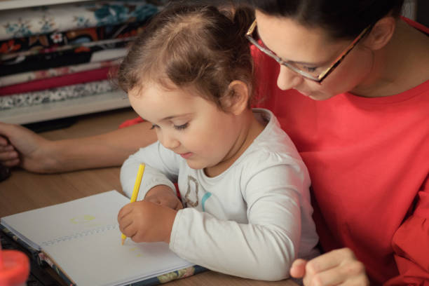 istock Small daughter drawing with her mother at home. 872192566