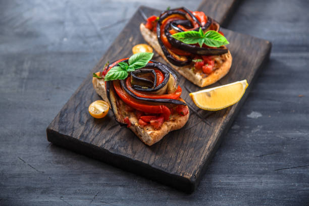 istock Two bruschettas with baked aubergines and peppers on black background 872193152