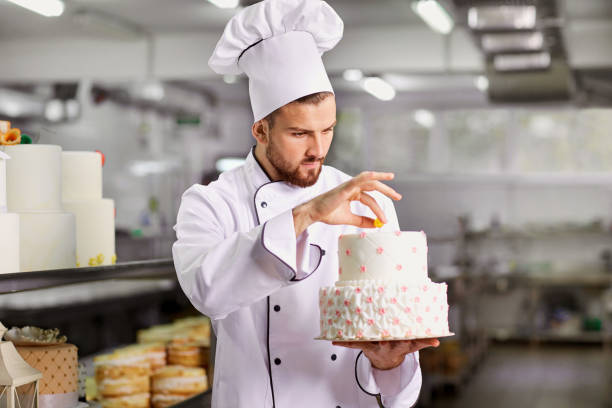 istock Chef pastry decorates cake in the kitchen. 872197284