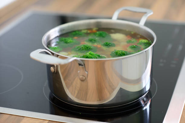 Nutritional soup with green broccoli in metal pan on hob